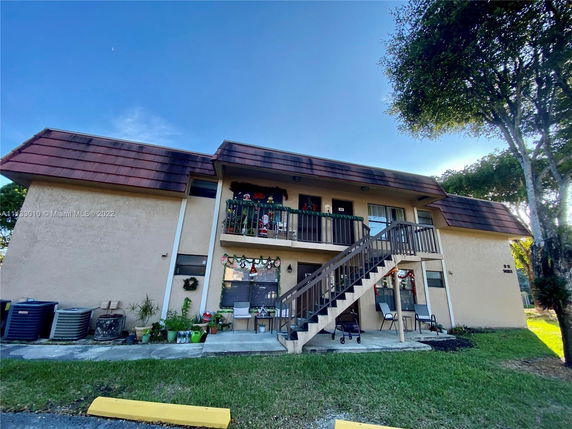 Front view of a two-story residential building with external staircase and balcony.