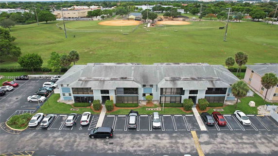 Aerial view of a residential complex with adjacent parking and nearby green spaces.