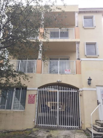 Front view of a multi-story building with balconies and a gated entrance.