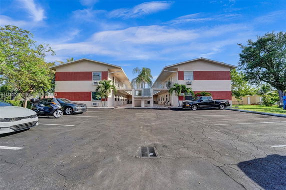 Parking area in front of a two-story building with red and beige exterior.