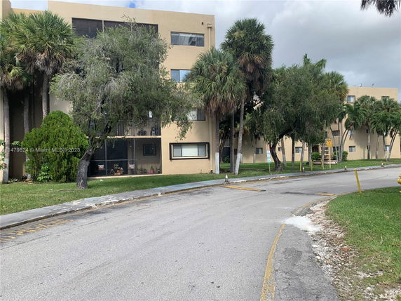 Front view of a multi-story residential building with trees in front.