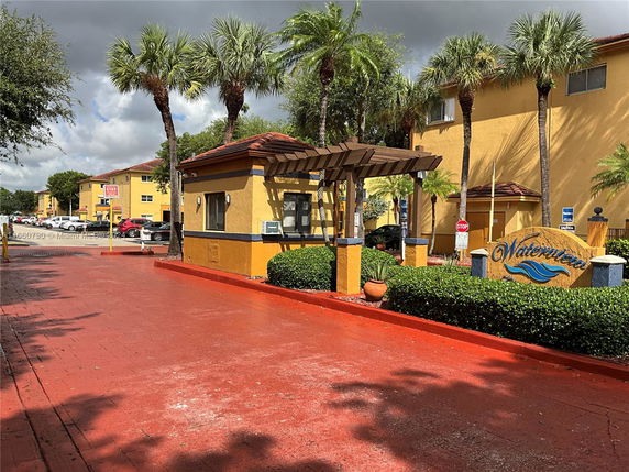 Entrance view of a residential area with apartment buildings and palm trees.