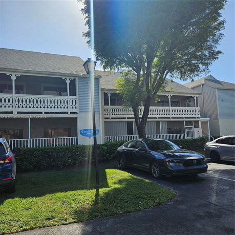 Front view of a two-story building with decorative white railings and a shingle roof.