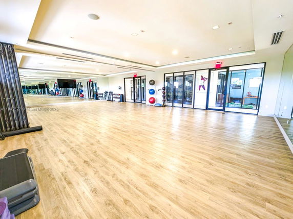 Spacious indoor fitness area with wooden flooring and exercise equipment.