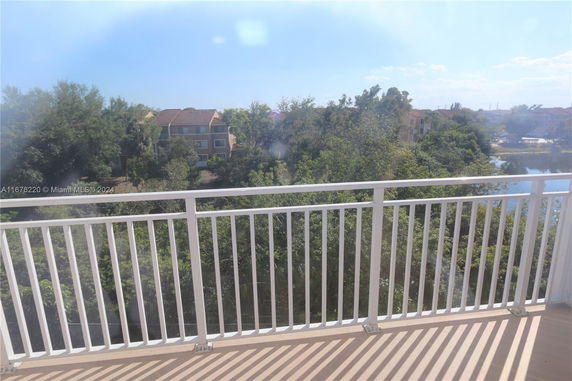 Balcony view showing surrounding residential buildings and trees.