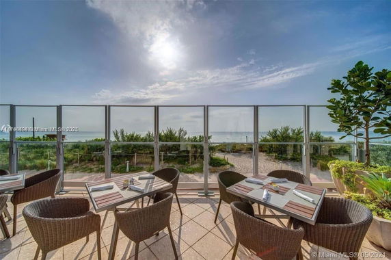 Outdoor dining area with tables and chairs overlooking the beach and ocean.