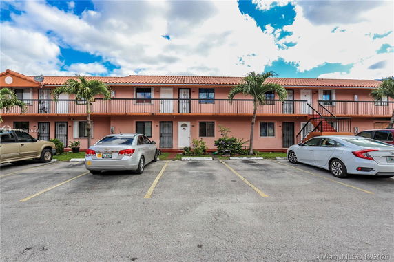 Front view of a two-story residential building with an outdoor parking area.