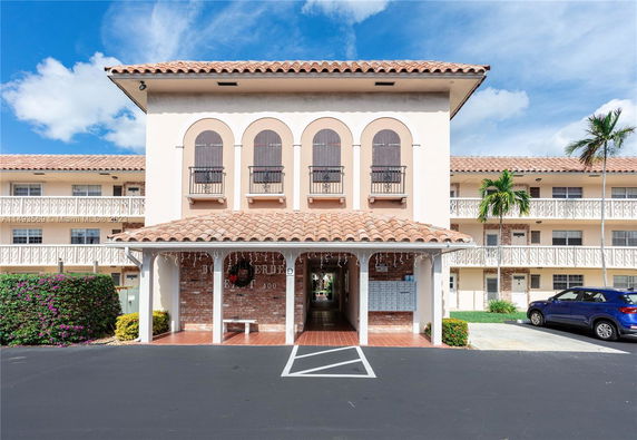 Front view of a multi-story building with arched windows and a tiled roof.