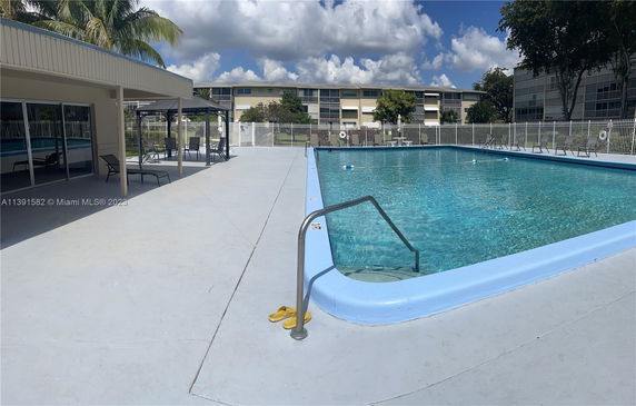 Outdoor swimming pool area with lounge chairs and a shaded seating section.