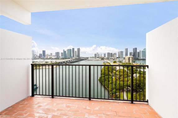 Panoramic view from a building balcony overlooking a city skyline across the water.
