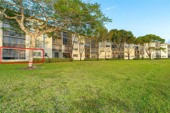 Front view of a multi-story residential building with screened balconies and large windows.