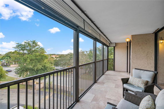 Balcony view overlooking street and trees, with seating area.