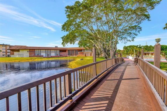 View of a building by a pond with a wooden bridge in the foreground.