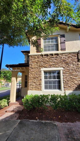 Front view of a two-story house with stone facade and large windows.