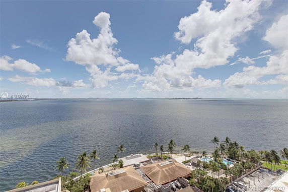 Panoramic view of the ocean with palm trees and buildings in the foreground.