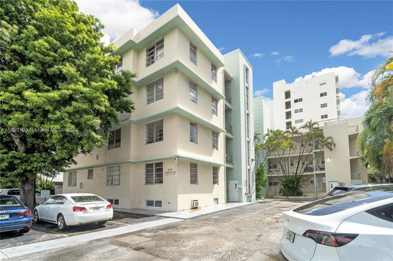 Front view of a multi-story residential building with parking area.