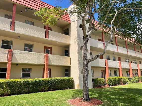 Front view of a multi-story building with balconies and a red tile roof.
