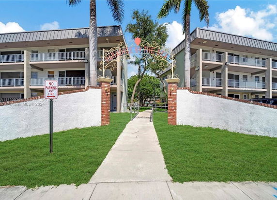 Front view of a multi-story residential building with a gated entrance and balconies.