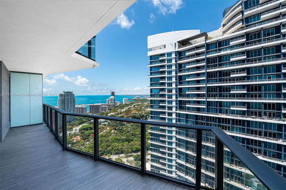 Panoramic view from a high-rise balcony showing surrounding cityscape and ocean.
