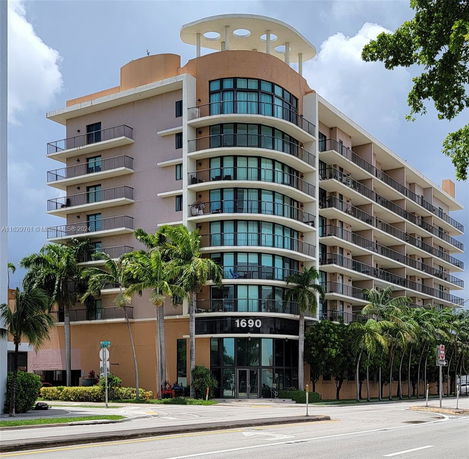Front view of a multi-story residential building with balconies and large windows.