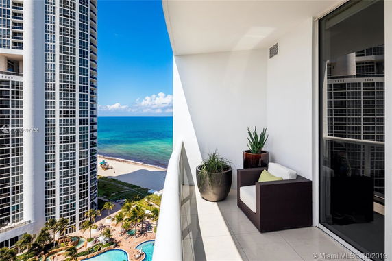 View from a balcony overlooking the ocean and adjacent high-rise building.