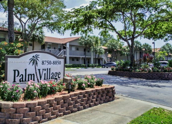 Front view of a multi-story apartment complex with a sign reading 'Palm Village'.
