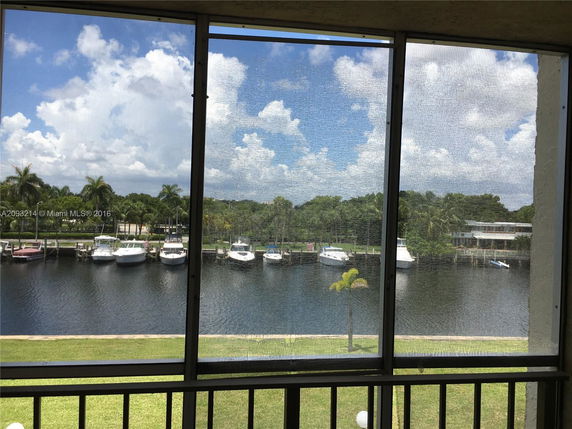 View from a building showing a waterfront with boats docked and palm trees.