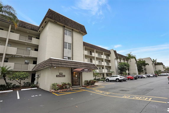 Front view of a multi-story apartment building with a parking area.