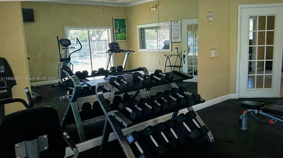 Indoor fitness area with exercise equipment and dumbbells.