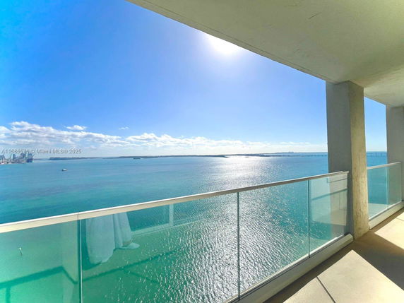 Panoramic view from a balcony overlooking a vast body of water and distant cityscape.