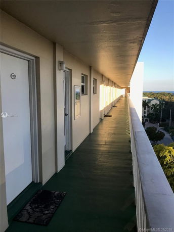 Exterior walkway of an apartment building with doors and overlooking a view of the surroundings.
