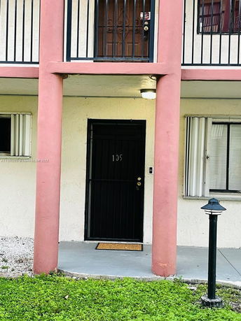 Front view of a two-story building with distinct red columns and black doors.