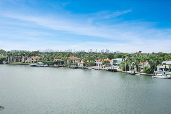 Wide angle view of waterfront residences with a city skyline in the background.