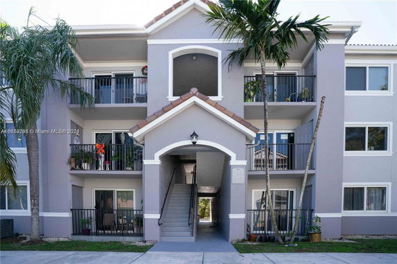 Front view of a three-story apartment building with balconies and an entrance archway.