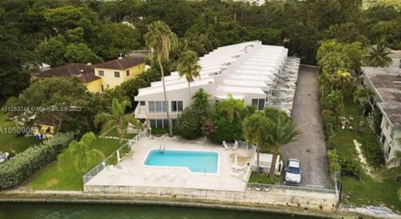 Aerial view of a residential complex with a swimming pool facing a waterway.