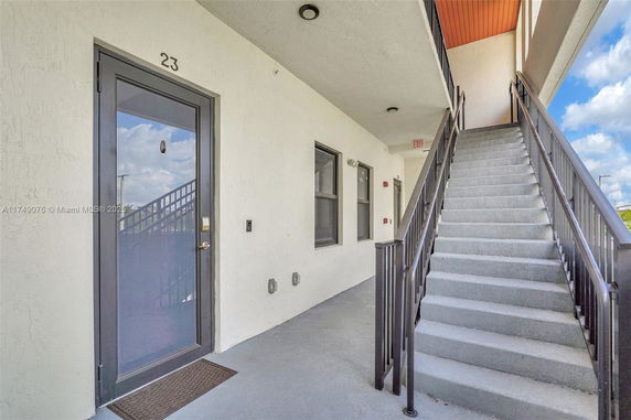 Exterior view of a building with a staircase leading to an upper level entrance.