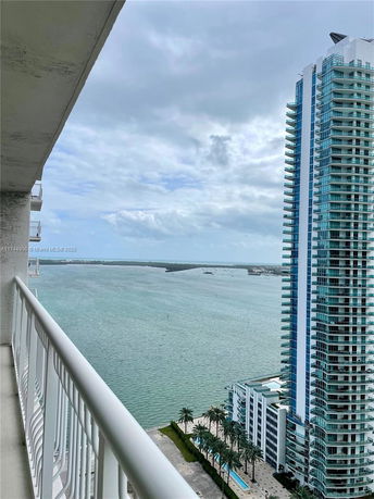 High-rise building with blue windows overlooking a large body of water from a balcony perspective.