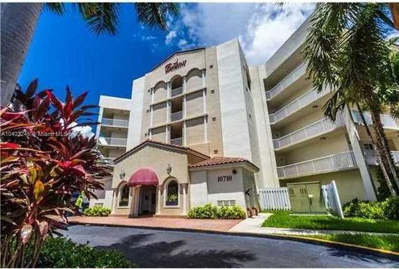 Front view of a multi-story residential building with arched balconies and a small entrance canopy.