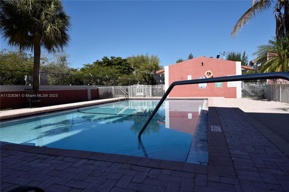 Outdoor swimming pool area with a red building in the background.