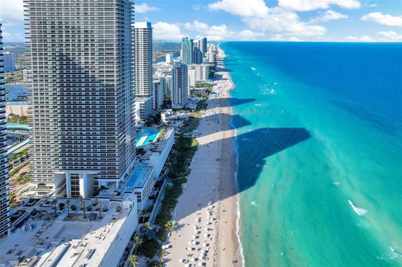 Aerial view of high-rise buildings along a coastline with a beach.
