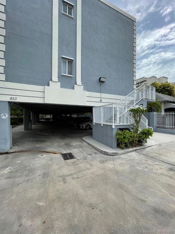Covered parking area under a multi-story building.