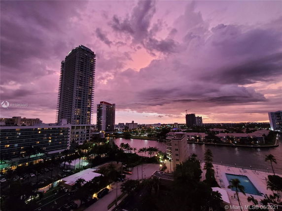 Skyline view of a city with high-rise buildings and a river during sunset.