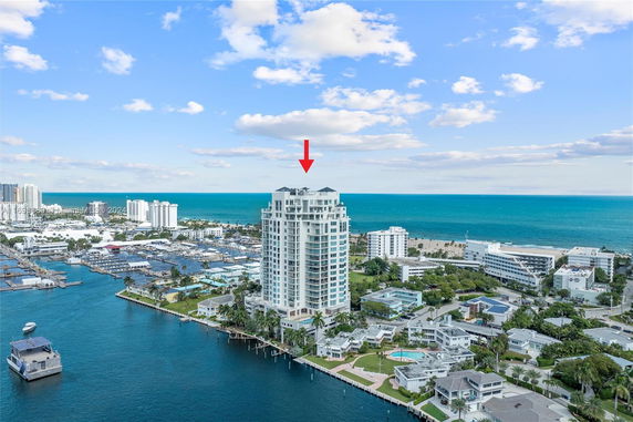 Aerial view of a high-rise building near the coastline with surrounding buildings and water.