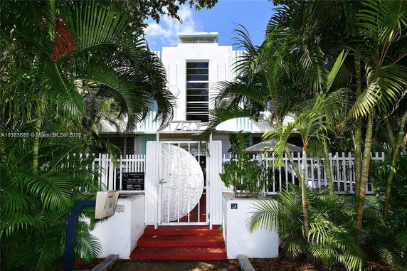 Front view of a multi-story building with decorative gate and palm trees.