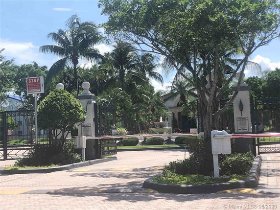 Entrance gate of a residential area with a fountain in the background.