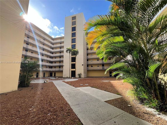Front view of a multi-story building with balconies and a central courtyard area.