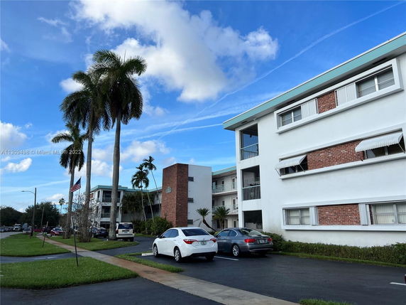 Front view of a multi-story residential building with parking spaces.