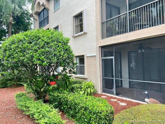 Front view of a multi-story building with screened balcony and landscaped area.