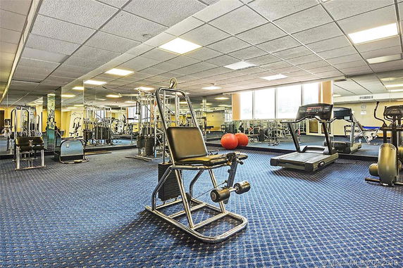 Indoor gym area with various exercise equipment and mirrored walls.