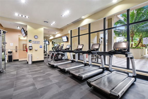 Indoor gym with treadmills and large windows.